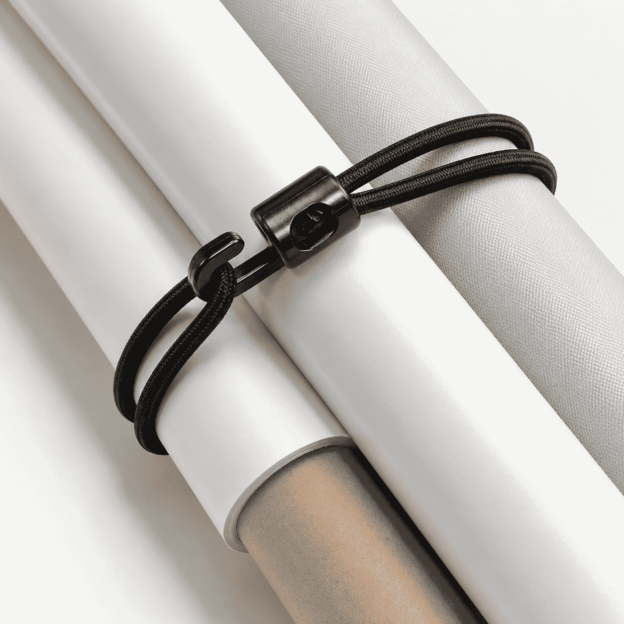 Die schwarze Spannschlaufe mit verstellbarem Stopper bündelt zusammengerollte helle Planen